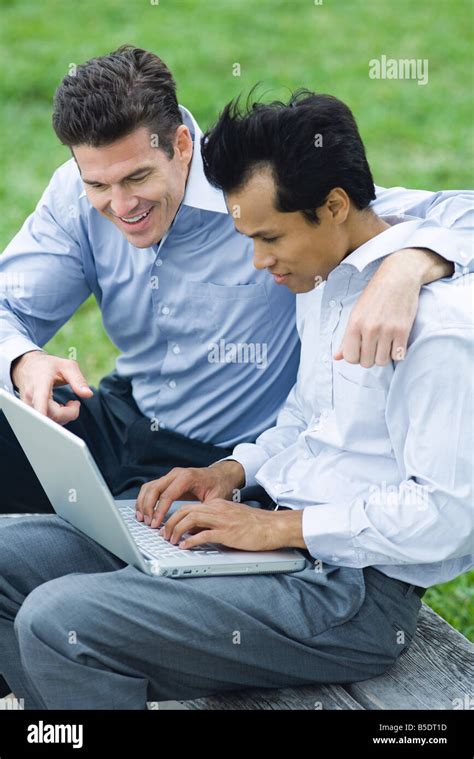 Business Partners Using Laptop Together Outdoors One Mans Arm Around