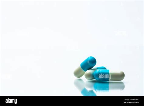 three blue and white capsules pills on white background with shadows and copy space for text