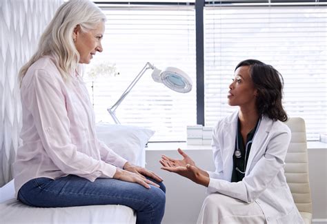 Mature Woman In Consultation With Female Doctor Sitting On Examination