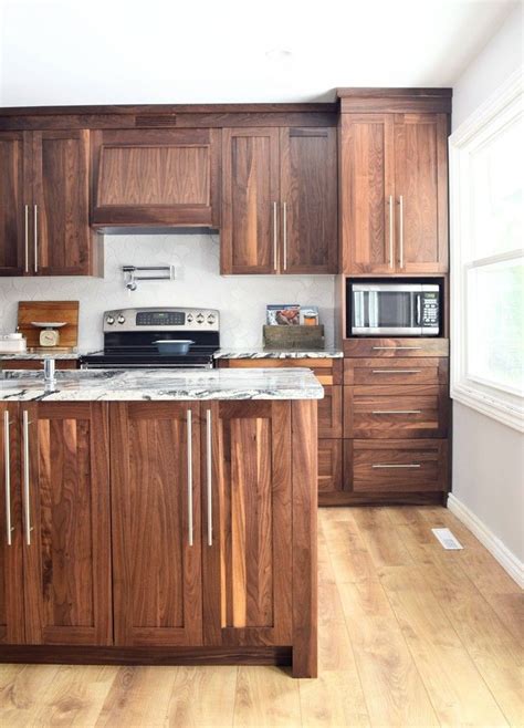 The kitchen cabinets are painted in an off white color with simple molding details, and the counter top is white carrara marble. Galley Kitchen remodel with walnut cabinets and marble-like White granite | Walnut kitchen ...