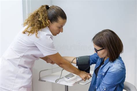 Nurse Taking Female Patient S Blood Pressure In Office Stock Image