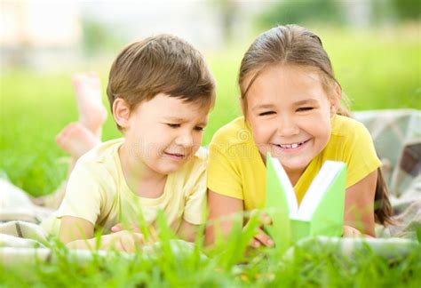 Little Girl And Boy Are Reading Book Outdoors Stock Photo Image Of