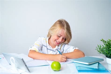 책상에 앉아 웃고 있는 중학교 소년 소녀 교실에서 글쓰기 책과 태블릿을 공부하고 있다 학교로 돌아 가기 어린 시절 교육 어린이를