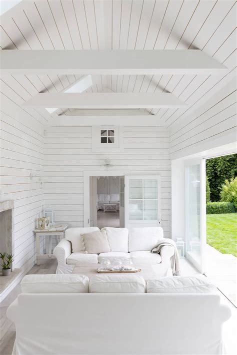 White Shiplap Living Room Showcases Facing White Sectional Sofas And A