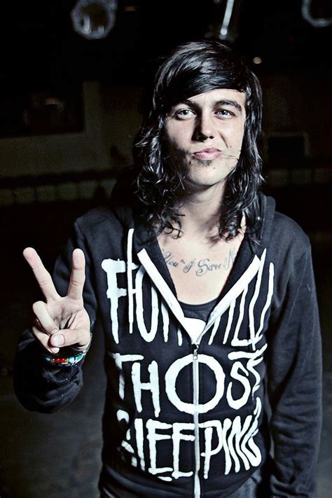 a man with long hair wearing a black hoodie and holding up two peace signs