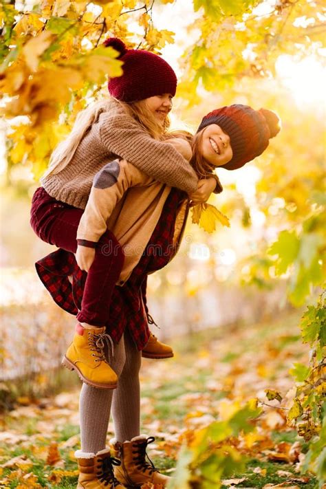 Two Girls In Hats Are Playing And Having Fun In Autumn Park Stock Photo