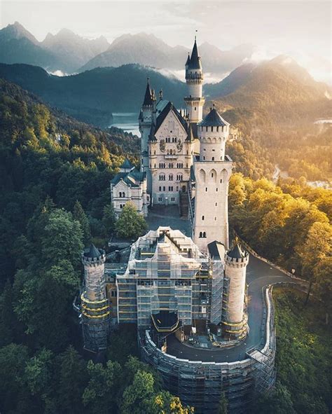 An Aerial View Of A Castle In The Middle Of Trees With Mountains In The