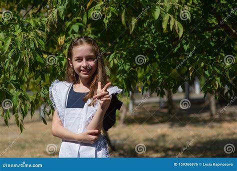 Schoolgirl Walks On A Lawn Among Tall Trees Front View Stock Photo