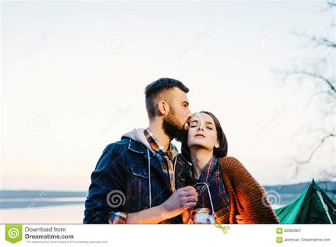 Man And Woman Lovers Hold A Flashlight At Dawn Near The Lake Stock