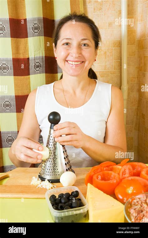 mature woman grating eggs in her kitchen see in series stages of cooking of farci tomato stock