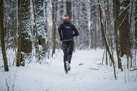 Photo From Back Of Running Athlete Among Trees In Winter Forest Stock