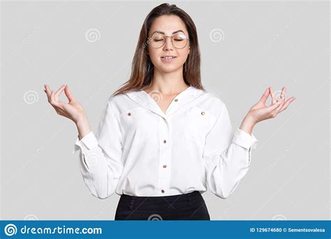 Photo Of Peaceful Calm Young Woman Holds Hands In Mudra Gesture Tries To Relax And Concentrate