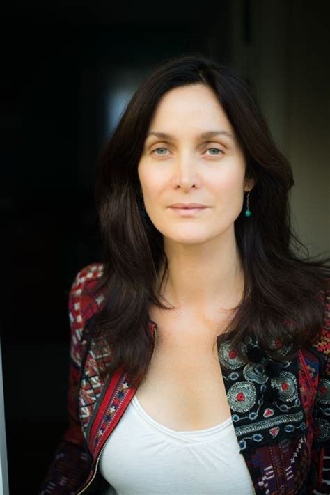 A Woman With Long Dark Hair Wearing A Jacket And White Top Is Looking