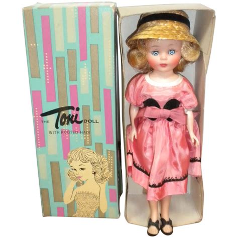A Doll In A Pink Dress And Straw Hat Is In A Box With The Lid Open