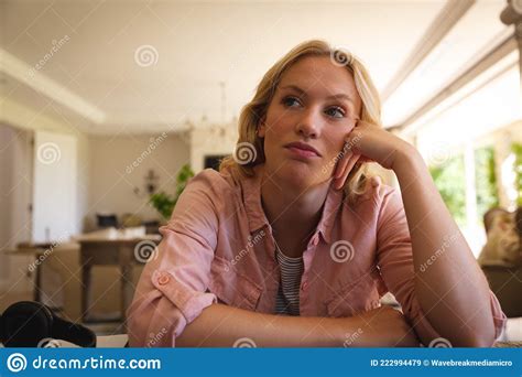 Caucasian Woman Sitting At Table Working In Living Room Leaning On