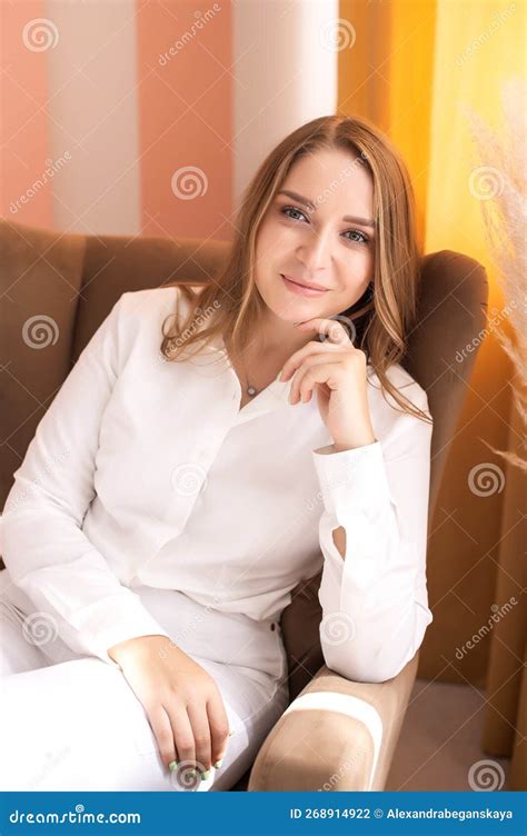 A Cute Girl Is Sitting In A Chair Her Hand Under Her Face Stock Photo