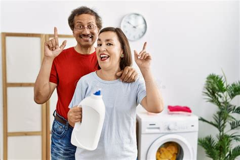 Middle Age Interracial Couple Doing Laundry Holding Detergent Bottle