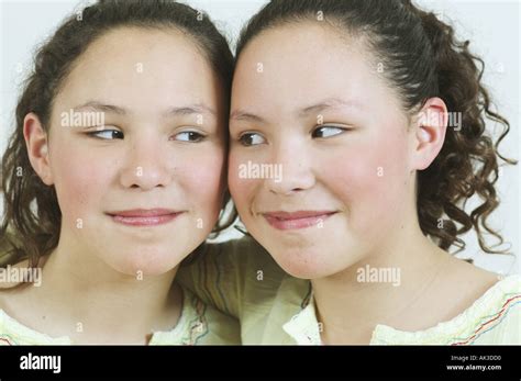 Close Up Portrait Of Teenage Twin Girls Looking At Each Other Stock
