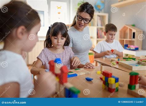 Preschool Teacher With Children Playing With Colorful Wooden Didactic
