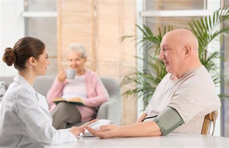 Nurse Measuring Blood Pressure Of Elderly Man Assisting Senior