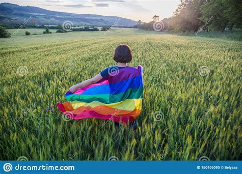 woman holding the gay rainbow flag on a green meadow outdoors happiness freedom and love