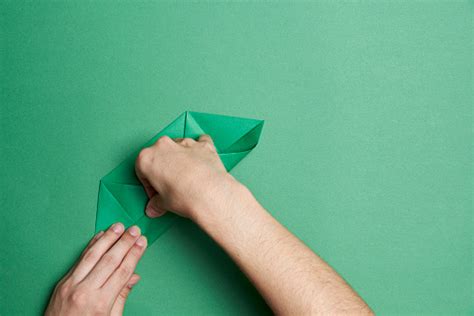 Young Hands Folding Paper To Make An Origami Figure Green Paper And