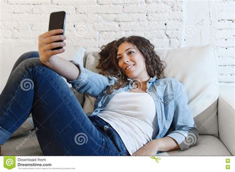 Young Attractive Hispanic Woman Lying On Home Couch Taking Selfie Photo