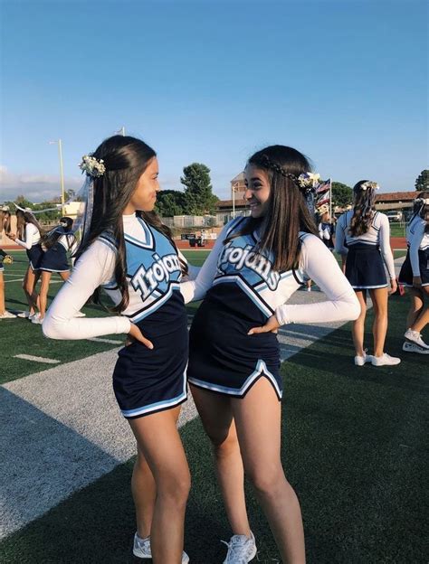 two cheerleaders are standing on the field