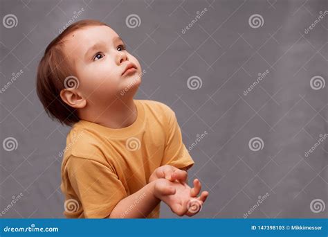 Little Toddler Boy In Yellow Shirt Standing And Looking Up Asking For