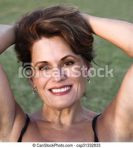 outdoor portrait of a beautiful mature woman pulling her hair back in the late evening light
