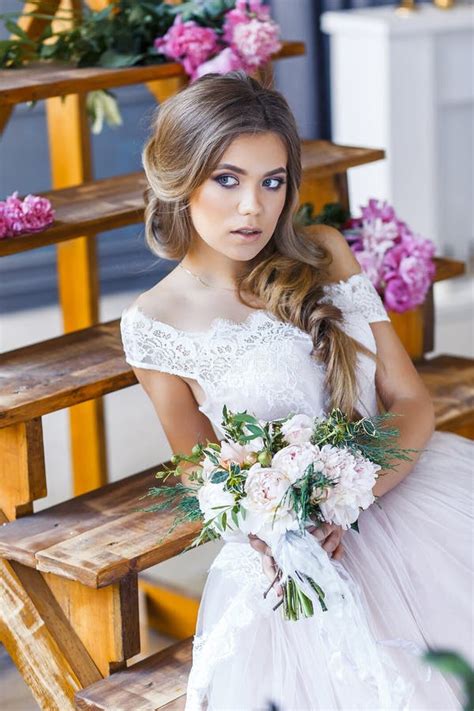 a bride with hairstyle and make up in gorgeous pink wedding dress and a vail with a bouquet of