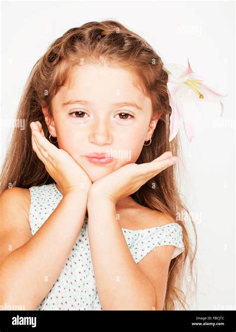 little cute beauty girl isolated on white background holding flower lily in her hair close up