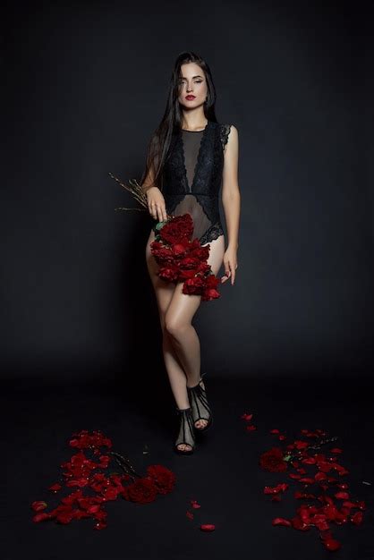 Sexy brünette mit einem strauß roter rosen auf dem boden lange haare
