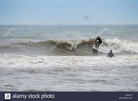 Two Surfers Riding A Wave In The Outer Banks North Carolina Stock Photo