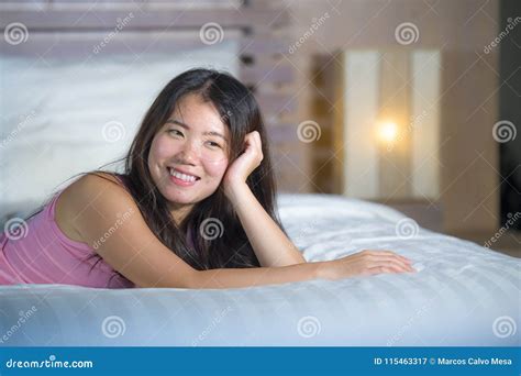 Young Beautiful And Sweet Asian Chinese Woman Lying Playful And Comfortable In Bed Relaxed And