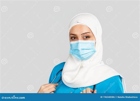 A Friendly Muslim Doctor Or Nurse In Hijab Mask On A Gray Background