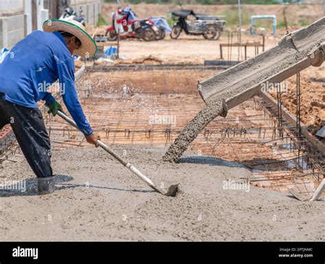 Worker Spreading Concrete With Rakes At Construction Site Stock Photo