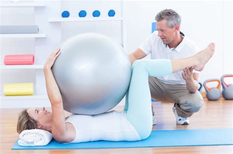 Premium Photo Therapist Helping His Patient With Exercise Ball