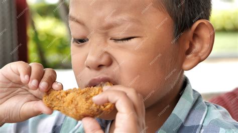 Premium Photo Cute Asian Boy Are Happy Eating Fried Chicken Leg In