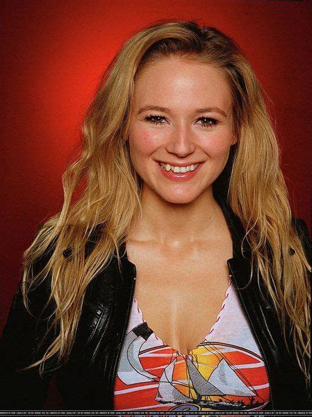 a woman with long blonde hair wearing a black leather jacket and smiling at the camera