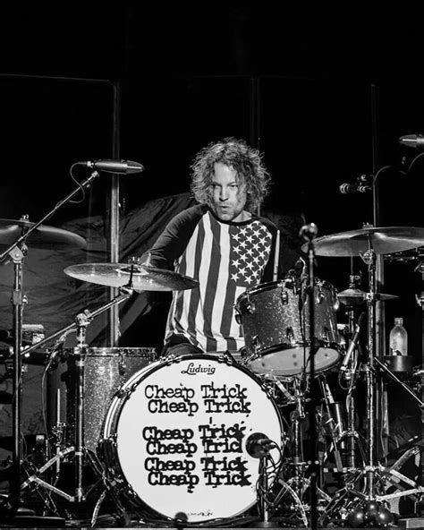A Man Playing Drums On Stage With An American Flag T Shirt Over His Shirt