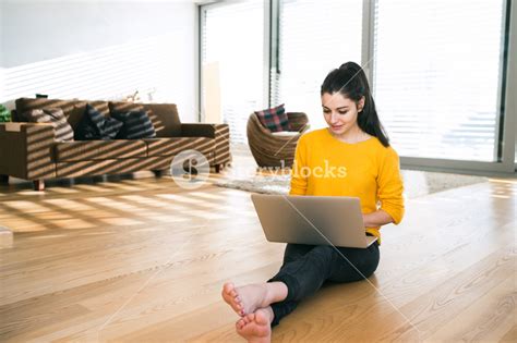 Beautiful Young Woman At Home Sitting On The Floor Working On Laptop