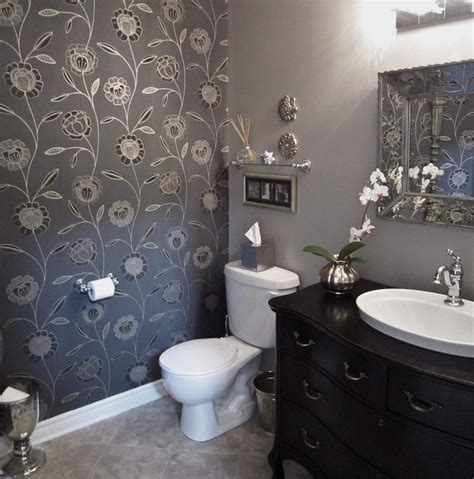Elegant contemporary powder room features a honed white marble and polished brass washstand completed with a round sink paired with a polished brass faucet positioned in front of a grid mirror mounted to a wall covered in gorgeous gray hand painted wallpaper. Elegant powder room photos
