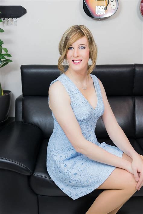 A Woman In A Blue Dress Sitting On A Black Leather Couch Next To A Clock