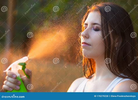 Young Woman Spraying Water On Herself From A Spray Bottle Close Up