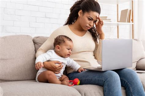 Madre Africana Cansada Con Bebé Llorando Usando Laptop En Casa Foto De