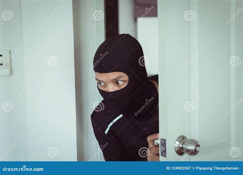Man Burglar In Black Mask Robber Stealing Computer From House Stock Image