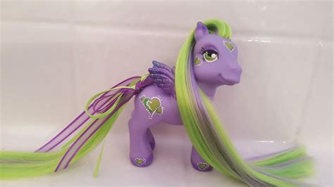 A Purple Pony With Long Green Hair On Its Head And Tail Sitting In A