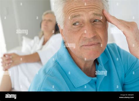 Couple In Bedroom Thinking Man In Foreground Woman Listening To Music With Headphones In