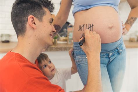 Man Writing Lines On His Wife Belly And Counting Pregnancy Weeks